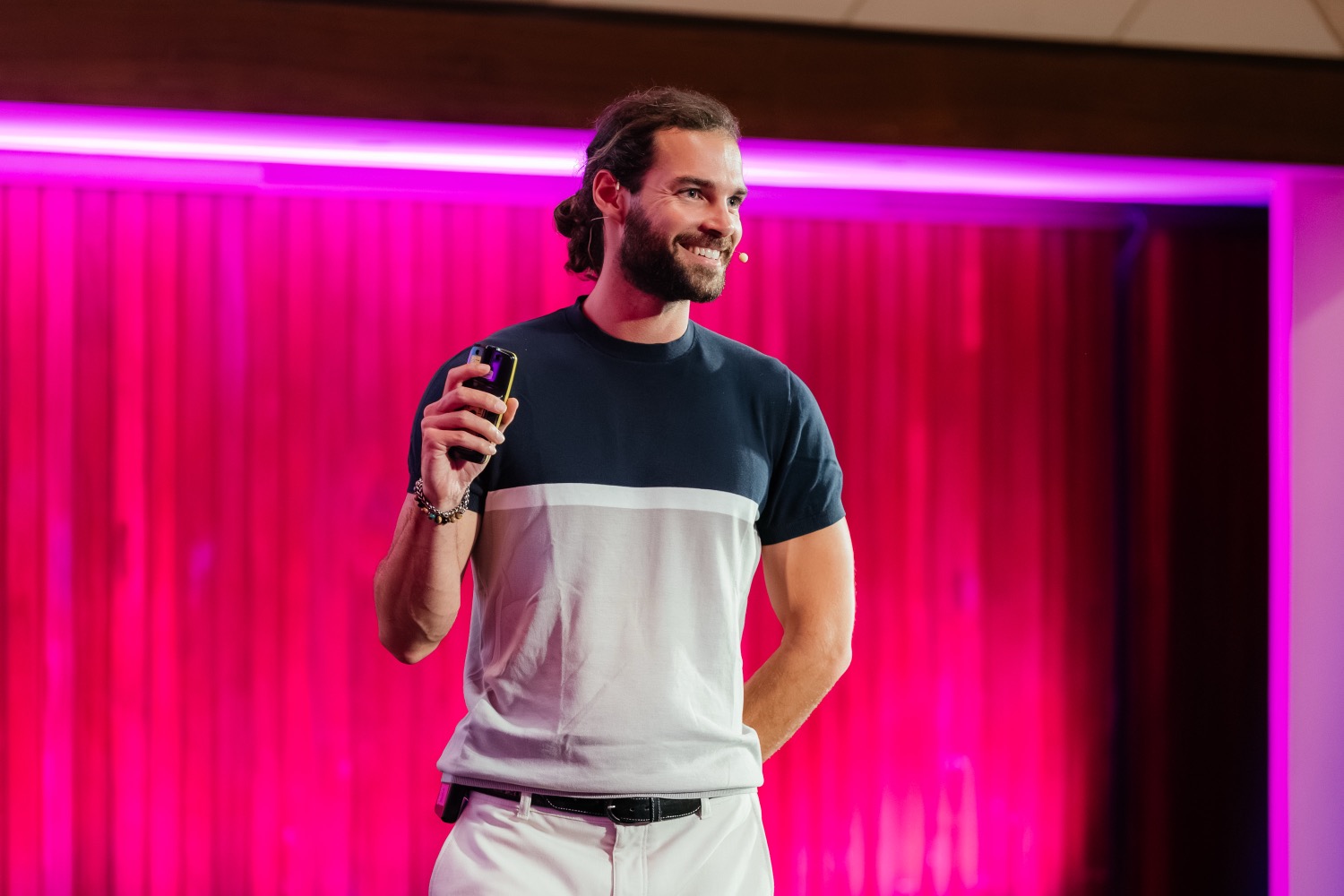 Rui Vas speaking on stage under magenta lighting